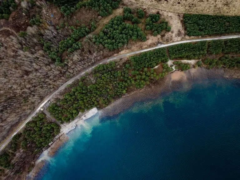 Gebogene Uferlinie von unten links nach oben rechts. Am ersten Abschnitt wurden bereits Wasserbausteine eingebracht, rechts im Bild ist die ausgespülte Uferlinie gut erkennbar.